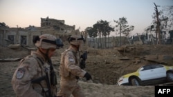 Croatian soldiers from the NATO coalition are walking past a crater from a bomb blast as they inspect the site of an attack targeting the German consulate in Mazar-e Sharif on November 11.