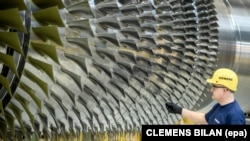 A worker stands next to a turbine at the Siemens Gas Turbine Plant in Berlin.