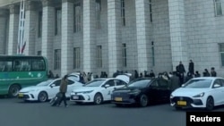خودروهای پارک شده با پلاک زردرنگ در بیرون از ایستگاه قطار پیونگ‌یانگ، پایتخت کره شمالی