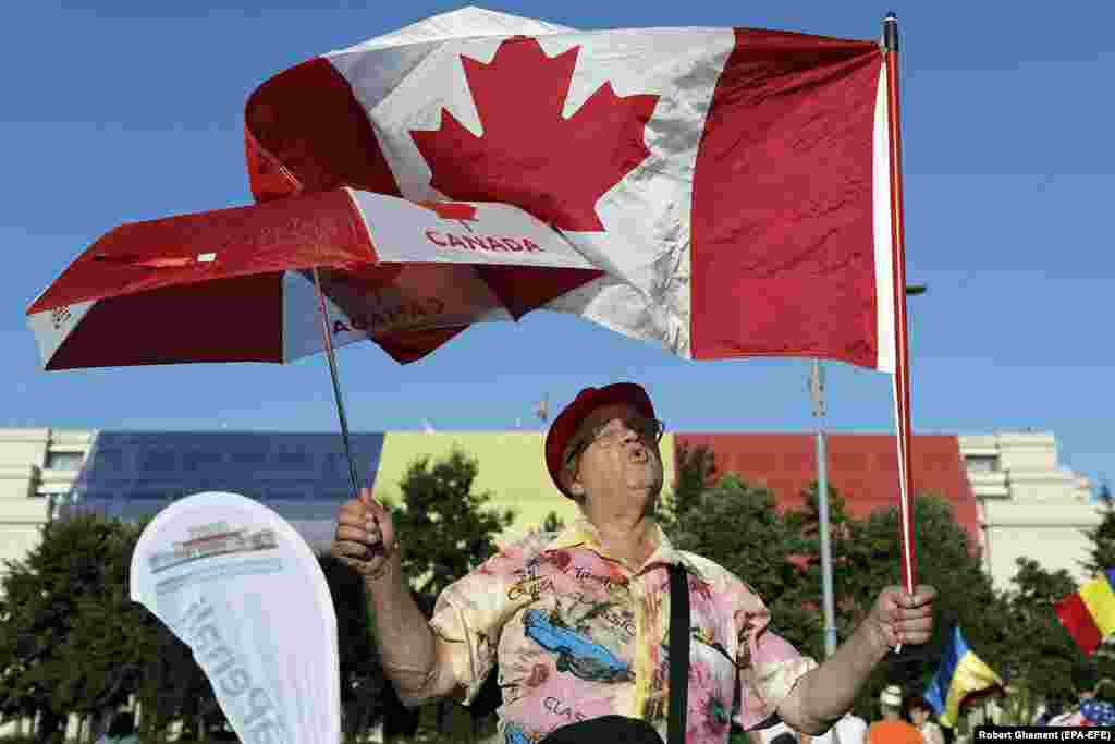 A protester waves a Canadian flag on August 12, as a third night of protests began. The protests have been dubbed the &quot;diaspora protests&quot; due to the number of Romanians who traveled home from abroad to take part in the demonstrations.