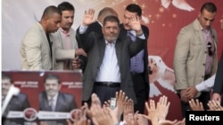 Egyptian President Muhammad Morsi (center) waves after speaking to supporters in front of the presidential palace in Cairo on November 23. 