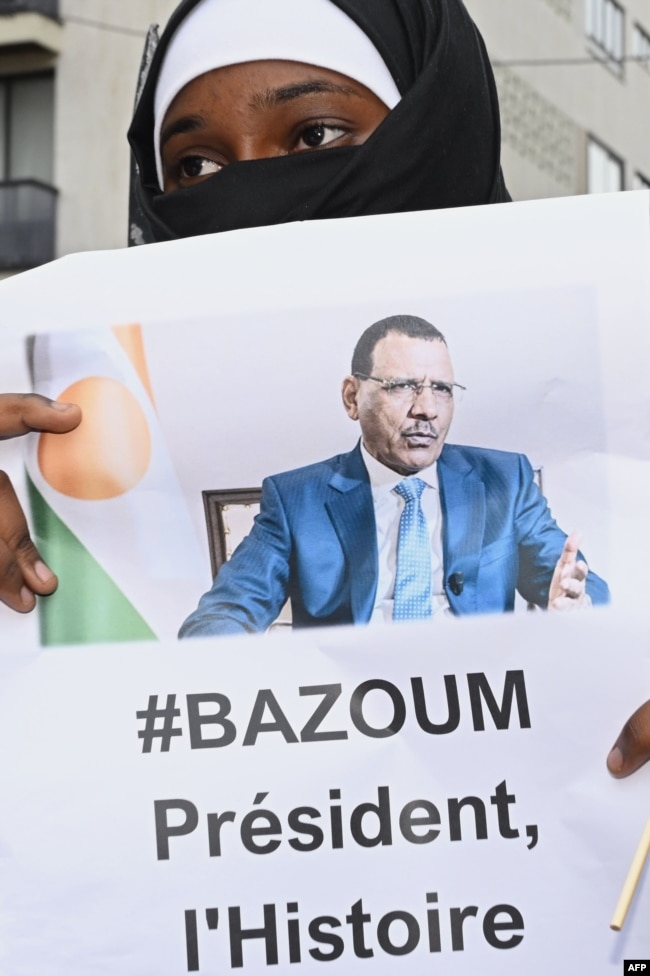 Një grua mban në dorë fotografinë e presidentit të rrëzuar të Nigerit, Mohamed Bazoum, gjatë një proteste pranë Ambasadës së Nigerit në Paris, 5 gusht 2023.
