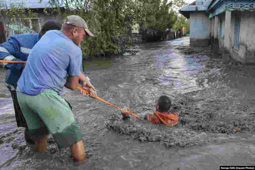 Двое мужчин пытаются спасти жителя, уносимого потоком воды в Галаце, Румыния