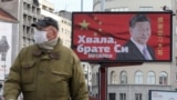 Serbia - A man wearing a protective mask passes by a billboard depicting Chinese President Xi Jinping as the spread of the coronavirus disease (COVID-19) continues in Belgrade, Serbia, April 1, 2020. 