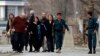 Afghan policemen evacuate foreigners from the site of an attack in Kabul on March 28.