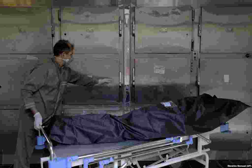 Медработник переносит тело пациента, умершего от COVID-19, в морг госпиталя Шохадайе Тайриш.