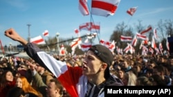 People wave old Belarusian republic flags during a rally commemorating the 1918 proclamation of independence from Russia in Minsk on March 25, 2018.