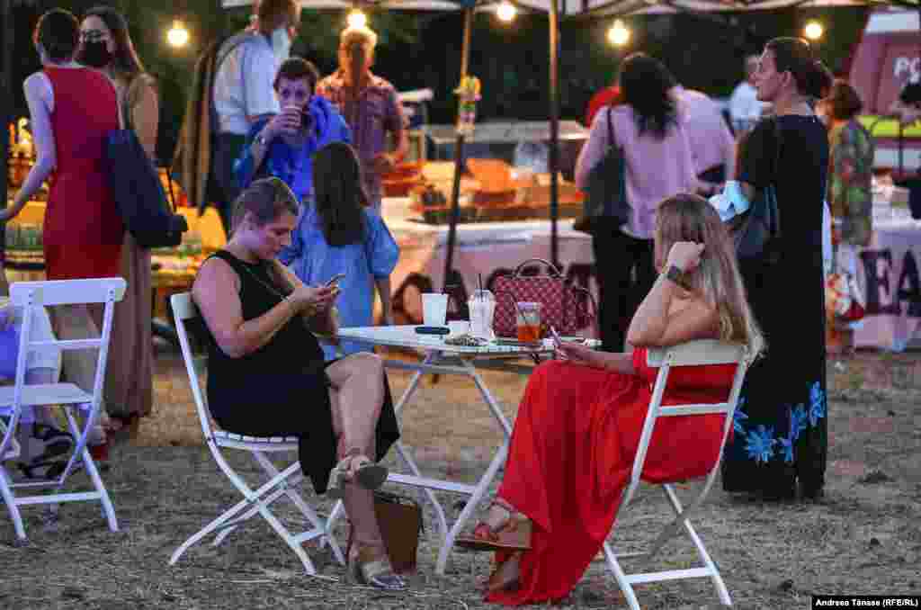 Două femei se relaxează în zona de food court de pe esplanada Operei Naționale din București.