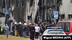 Police and rescue crews respond to the site where the plane carrying Romanian billionaire Dan Petrescu and his family crashed into an empty office building near Milan. 