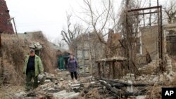Ռուս անջատականների հսկողության տակ գտնվող Դոնբասի շրջանի բնակիչները հրետակոծությունից ավերված տան մոտ, Դոնեցկի արվարձան, 9 ապրիլի, 2021թ. 