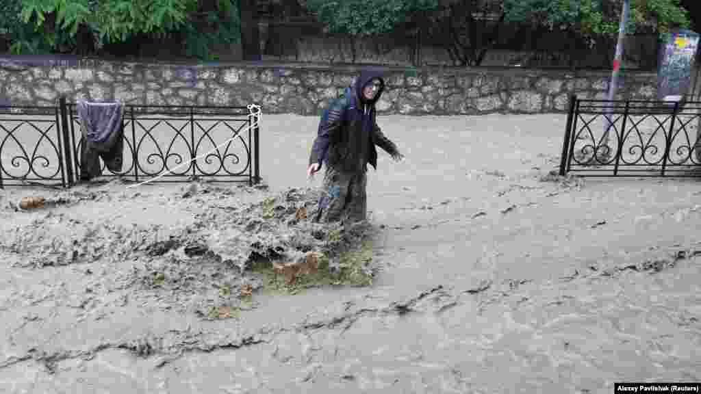 Мужчина стоит по колено в воде на одной из затопленных улиц Ялты