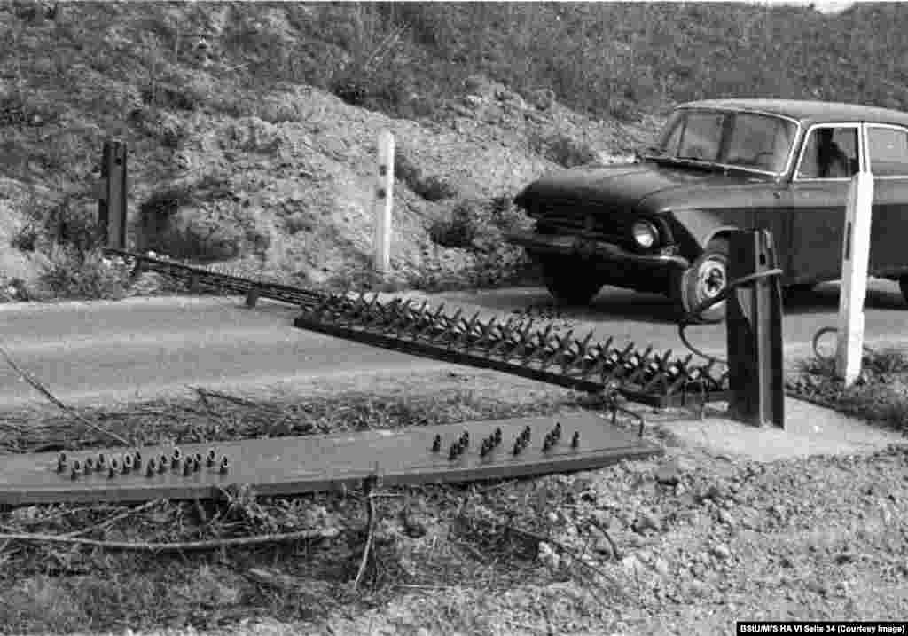 A car is driven towards a row of spikes as another tire-piercing plate awaits its trial at the Stasi&#39;s secret test facility in 1980.&nbsp; &nbsp;