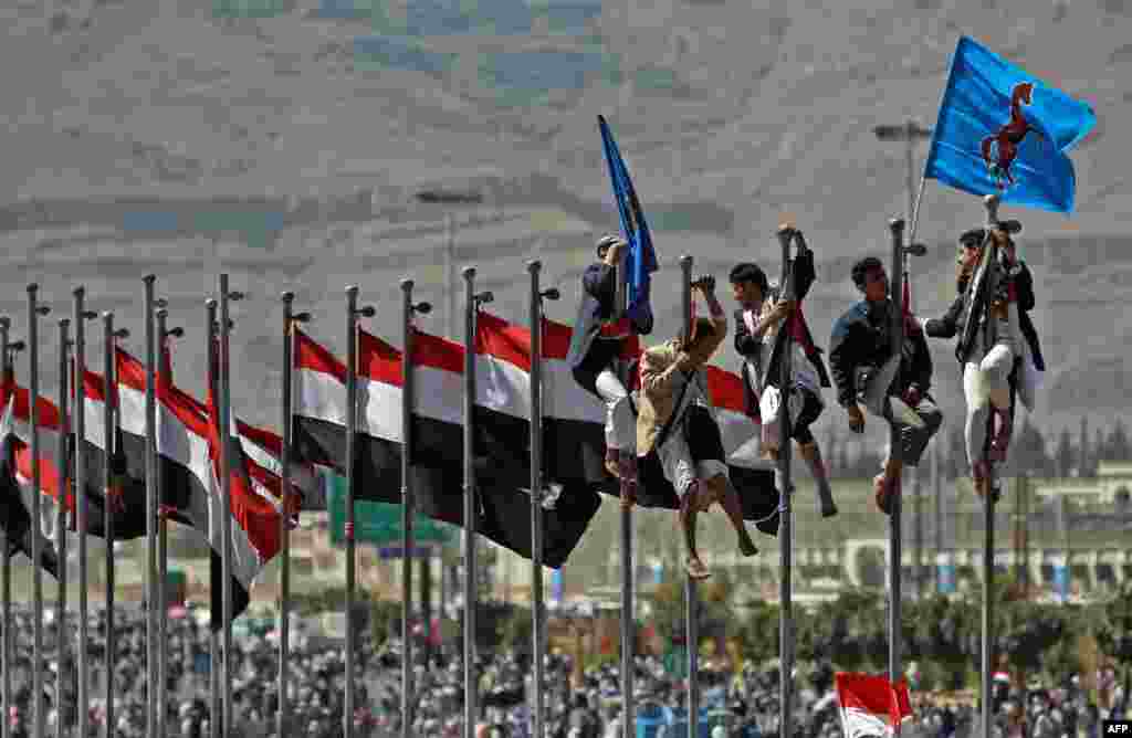 Supporters of former Yemeni President Ali Abdullah Saleh climb up flagpoles during celebrations on the occasion of the first anniversary of the handover of power in Sanaa. Saleh stepped down after 33 years at the helm in February 2011 and formally handed power to his then deputy, Abdrabuh Mansur Hadi. (AFP/Mohammed Huwais)
