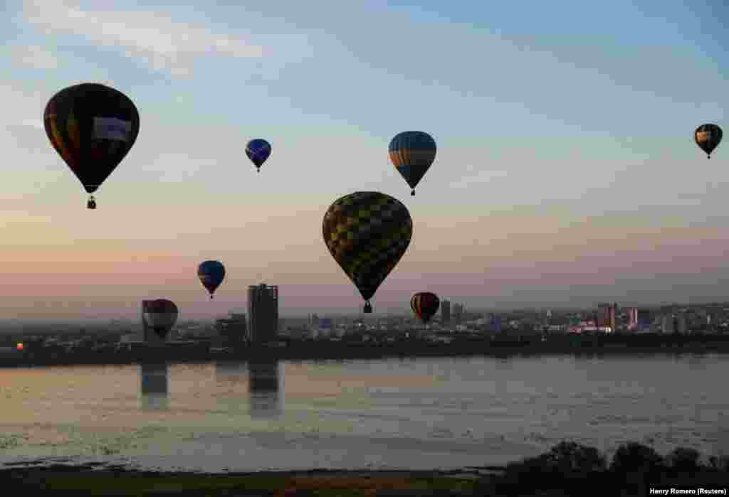 Balonat me ajër të nxehtë teksa fluturojnë mbi ujërat pranë një vendbanimi, gjatë festivalit.