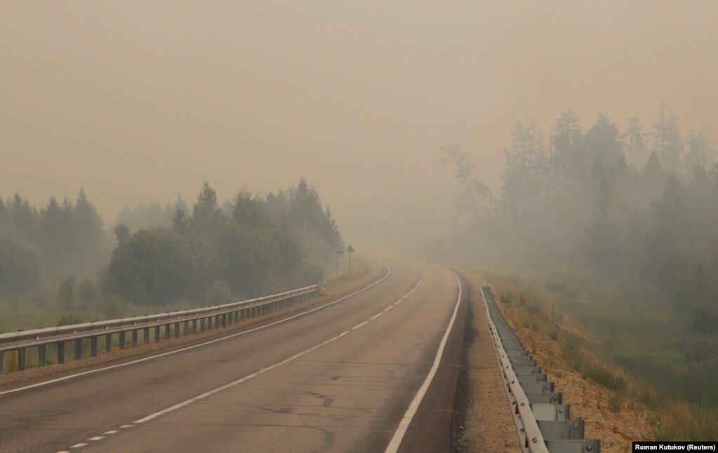 Smoke covers a road as a forest fire burns near the village of Magaras.