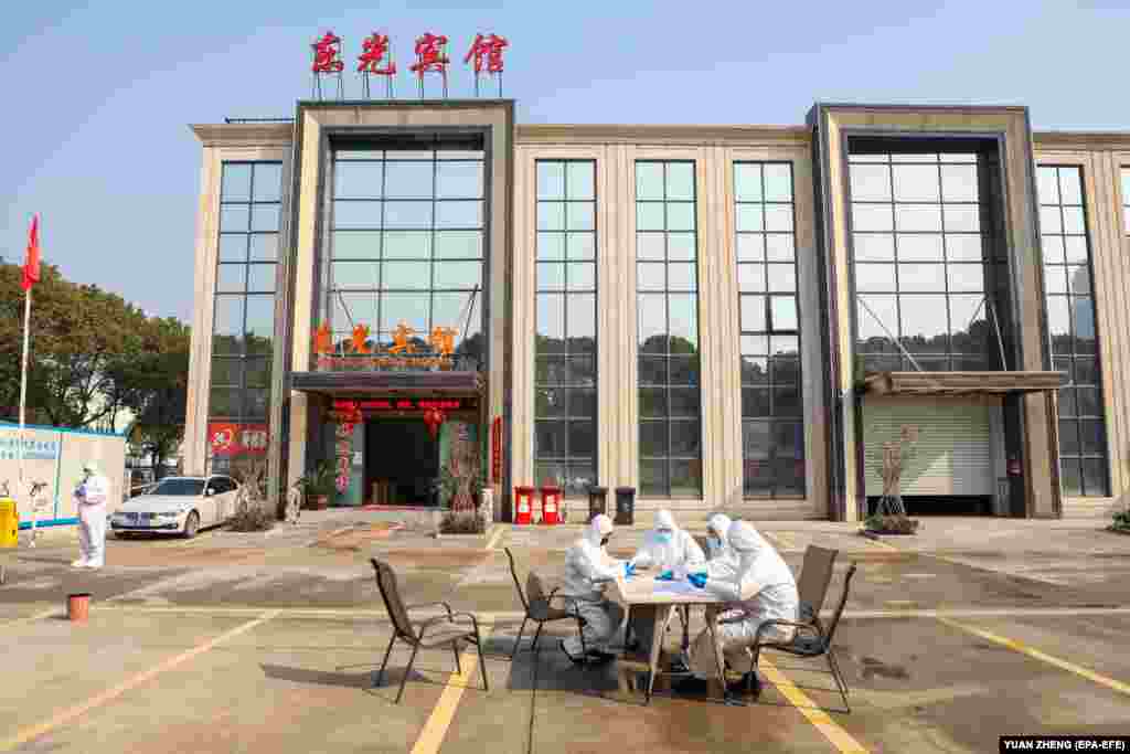 People in overalls talk at a table outside a hotel accommodating isolated people in the Chinese city of Wuhan. (epa-EFE/Yuan Zheng)