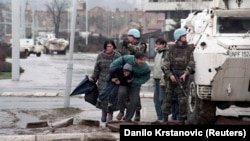 Stanovnici Sarajeva skrivaju se od snajperske vatre iza oklopnog vozila UNPROFOR-a u centru Sarajeva, 1993.