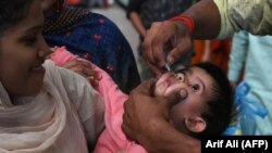 A Pakistani health worker administers polio drops to a child at a railway station during a polio vaccination campaign in Lahore on November 5.