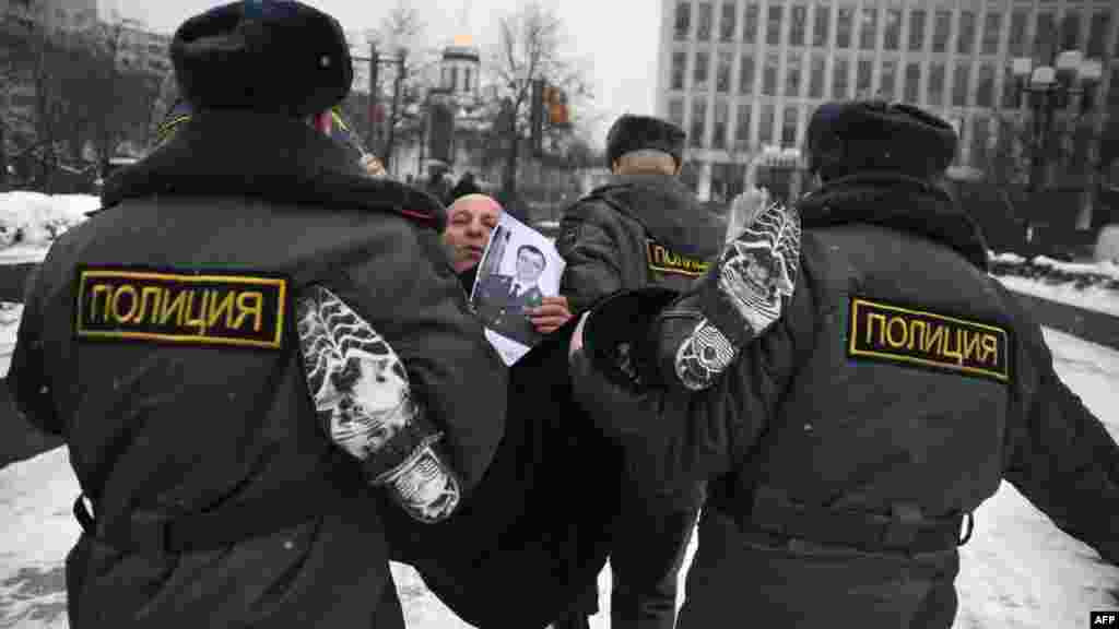 Russian Police officers detain an anticorruption protester holding a photo of Interior Minister Rashid Nurgaliyev, just outside the Interior Ministry headquarters in Moscow on January 18. (AFP/Andrey Smirnov)