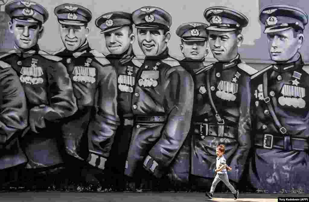 A boy runs in front of a mural dedicated to World War II Soviet pilots in downtown Moscow. (AFP/Yuri Kadobnov)&nbsp;