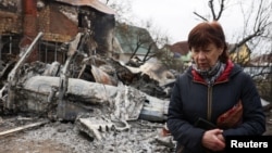 A woman in Kyiv on February 25 walks past a building damaged during Russia's massive military operation against Ukraine. 