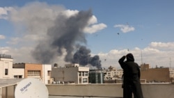 زنی در حال مشاهده دود ناشی از بمباران روز یکشنبه تهران از پشت بام