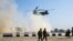 US troops walk as a US Army C-47 Chinook helicopter flies over the village of Oreij, south of Mosul, February 22, 2017