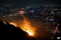 Un elicopter al pompierilor aruncă apă pe Hollywood Hills în Los Angeles, locul unde se află emblema Hollywood.