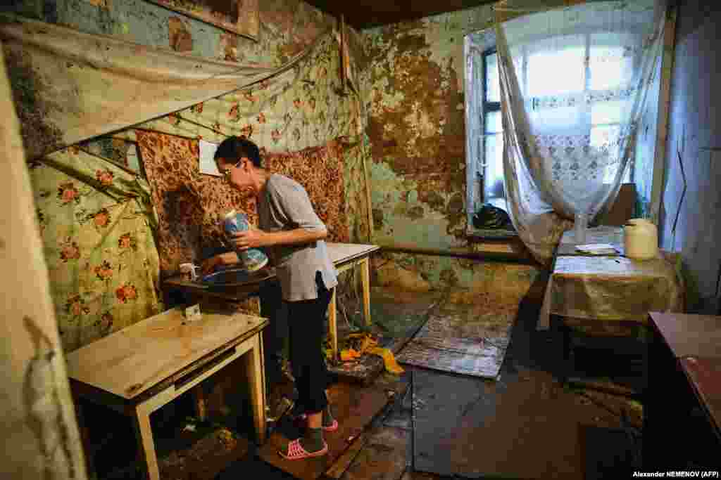 Женщина готовит на общей кухне. Как и большая часть коммунального жилья, это место перестало быть раем для рабочих после распада СССР, так как в конце 90-х текстильная фабрика закрылась из-за невозможности конкурировать с продукцией из Китая
