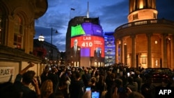 Qytetarë të Londrës duke shikuar rezultatin e "exit poll"-it të zgjedhjeve parlamentare, në një rrugë të qytetit, më 4 korrik 2024.