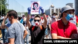 A man holds up a sign showing Gulshat Asylbaeva, a member of parliament, during a protest in June against the "false information" bill they say will imperil press and Internet freedoms in the country. Asylbaeva authored the bill.