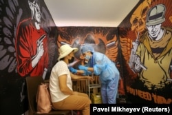 Женщина получает дозу вакцины от COVID-19 во временном прививочном отделении бывшей студии TikTok в торговом центре MEGA Park в Алматы, 23 июня 2021 года