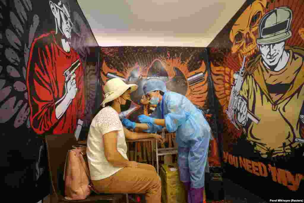 A woman receives a dose of a COVID-19 vaccine at a temporary vaccination unit set up at a former TikTok studio in the MEGA Park mall in Almaty, Kazakhstan.