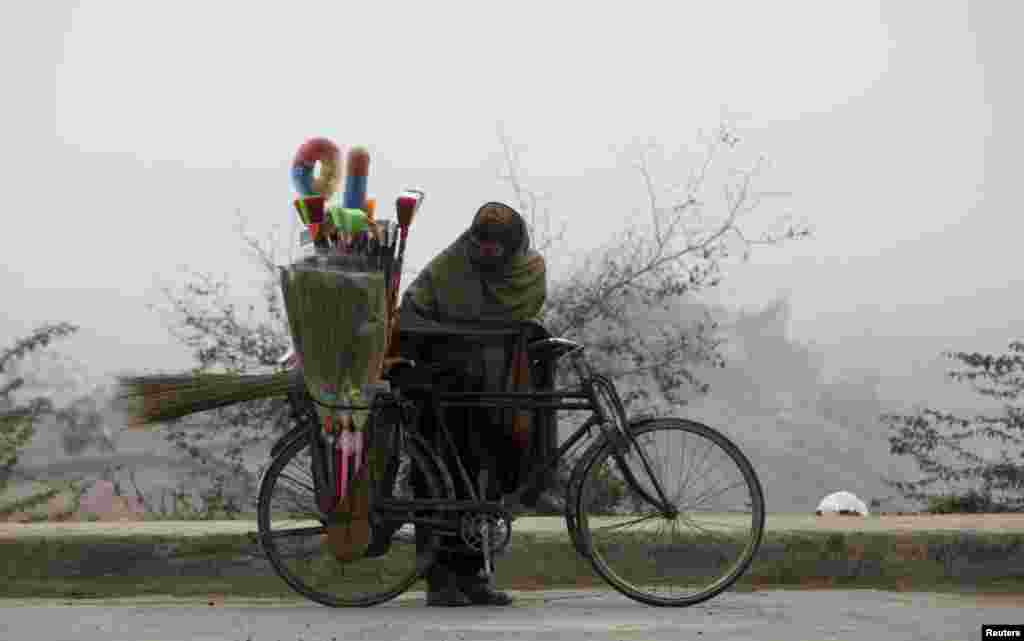 A brush salesman checks the load on his bicycle as he prepares to ride in the morning fog in Lahore, Pakistan. (Reuters/Mohsin Raza)