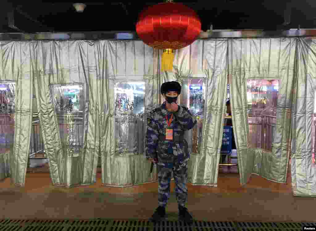 A Chinese security worker wearing a mask stands guard outside a checkpoint at the Beijing West Railway Station. (Reuters)