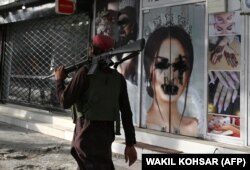 Озброєний таліб на тлі спотворених рекламних зображень жінок. Кабул.19 серпня 2021 року