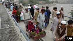 An Afghan man pushes a cart with a woman and children as they cross the border between Afghanistan and Pakistan in the Torkham (file photo).