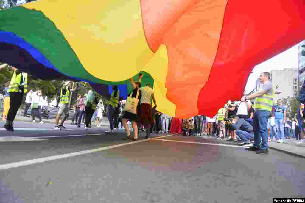 Disa pjesëmarrës shihen nën flamurin e komunitetit LGBT.