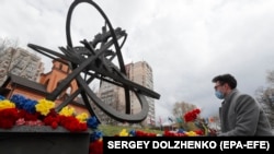 Украинцы возлагают цветы к памятнику в честь погибших при ликвидации последствий аварии на Чернобыльской атомной электростанции в Киеве, Украина, 26 апреля 2021 года.