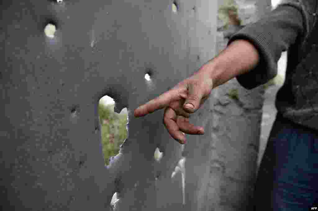 Житель азербайджанского города Тартар показывает дыры в поврежденных от обстрелов воротах