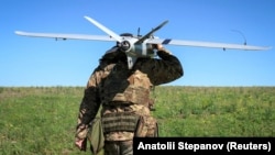Військовий батальйону безпілотних літальних апаратів «Корсар» 38-ї окремої бригади морської піхоти несе розвідувальний БПЛА «Лелека» українського виробництва перед його запуском поблизу лінії фронту. Донеччина, 22 травня 2026 року