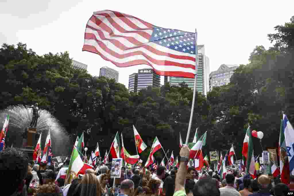 مردی با پرچم آمریکا در کنار ایرانیان شرکت‌کننده در تجمع سیدنی.