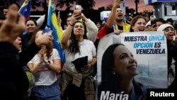 Oameni cu un portret al Corinei Machado la Miami, după ce SUA l-au capturat pe președintele Venezuelei, Nicolas Maduro, ca să-l judece pentru „narcoterorism” și alte acuzații. 