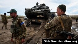 Українські військовослужбовці вантажать трофейний російський танк на вантажівку. Біля міста Ізюму на Харківщині, 24 вересня 2022 року