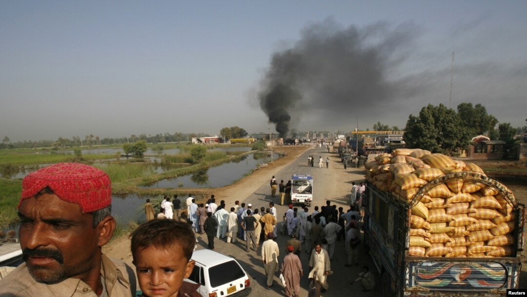 Passengers sat on the roof of a bus near burning oil tankers that were attacked by militants on October 1 near Shikarpur, Pakistan.