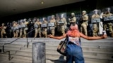 Un protestatar în fața unei linii a Gărzii Naționale din California care protejează o clădire federală în centrul orașului Los Angeles. Luni, 9 iunie 2025.