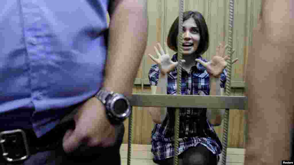 Nadezhda Tolokonnikova, a member of the female punk band Pussy Riot, which is accused of hooliganism, gestures as she sits behind bars during a court hearing in Moscow. (Reuters/Denis Sinyakov)