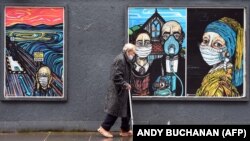 Egy idős férfi híres műalkotások maszkos graffitije előtt sétál el Glasgow-ban, 2020. szeptember 2-án 