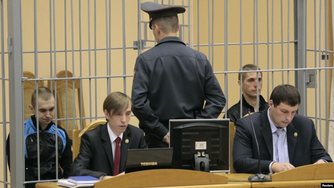 Dzmitry Kanavalau (left) and Uladzislau Kavalyou sit in a cage before court hearings in Minsk in September 2011.
