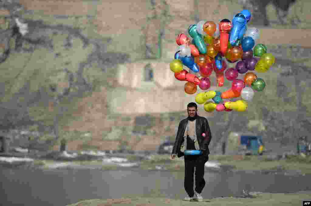 An Afghan man carries balloons as he walks at Shuhada Lake in Kabul. (AFP/Wakil Kohsar)